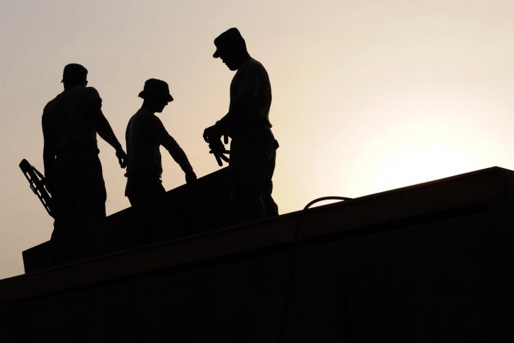 silhouette of workers on roof